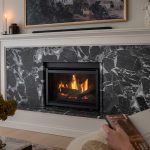 Modern fireplace with marble surround, cozy fire burning, and a person reading in the foreground. Warm and inviting ambiance.