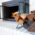 Firewood stacked on a white brick hearth beside an open fireplace.
