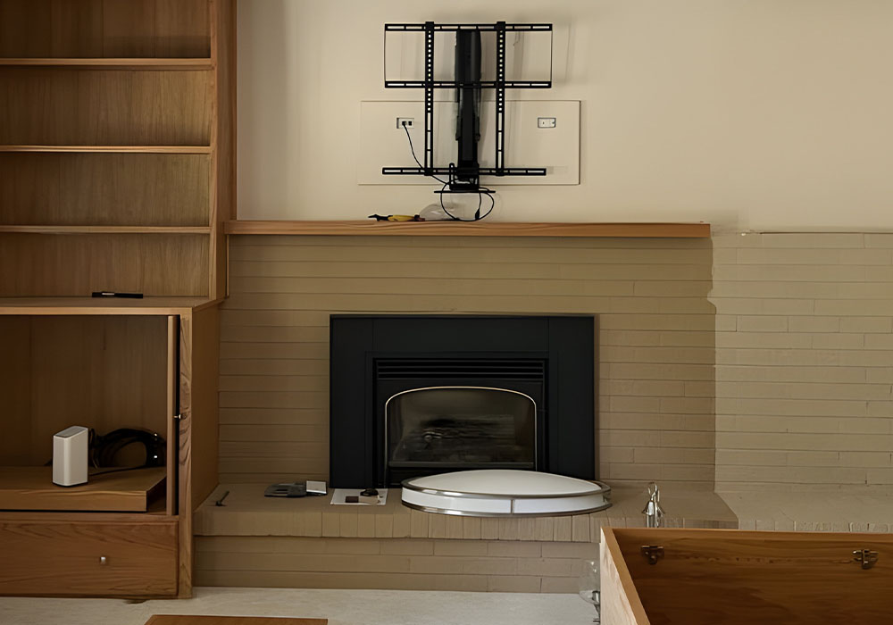 Empty TV wall mount above a modern fireplace with wooden shelves and cabinets.