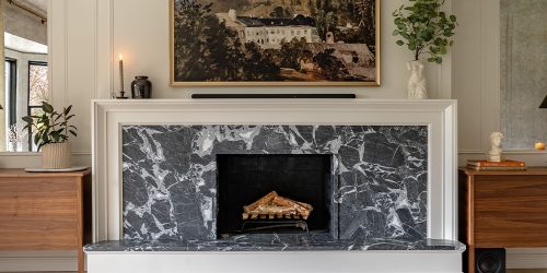 Elegant modern living room with dark marble fireplace, framed artwork, and minimalist decor for a cozy ambiance.