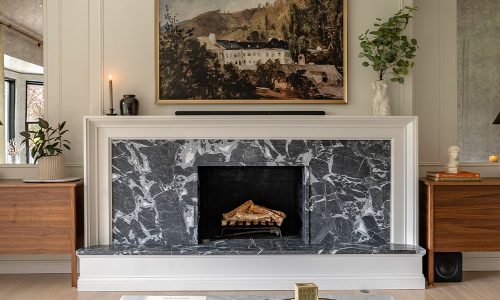 Elegant modern living room with dark marble fireplace, framed artwork, and minimalist decor for a cozy ambiance.